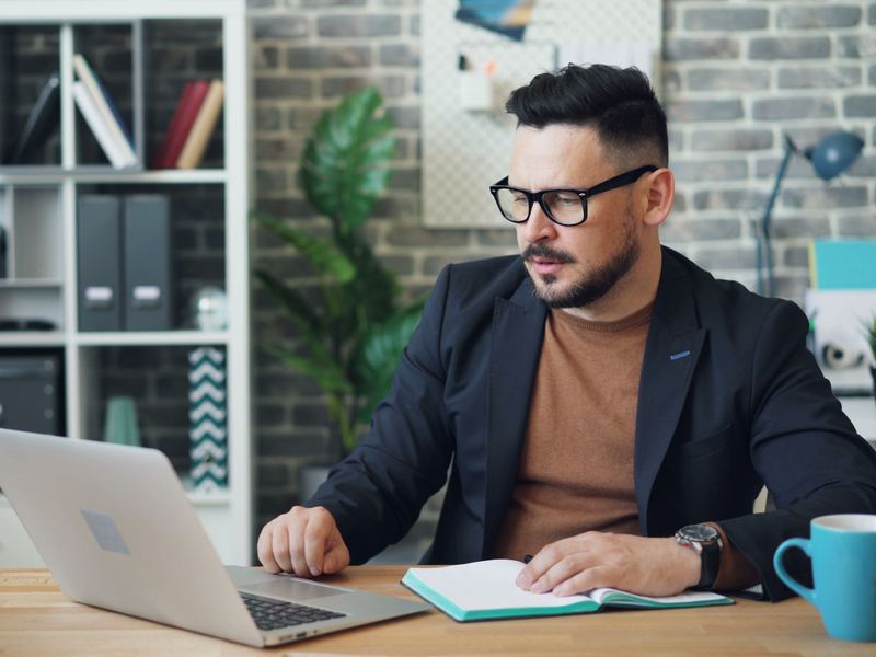 Komoly arcú cégvezető a laptopja előtt egy irodában